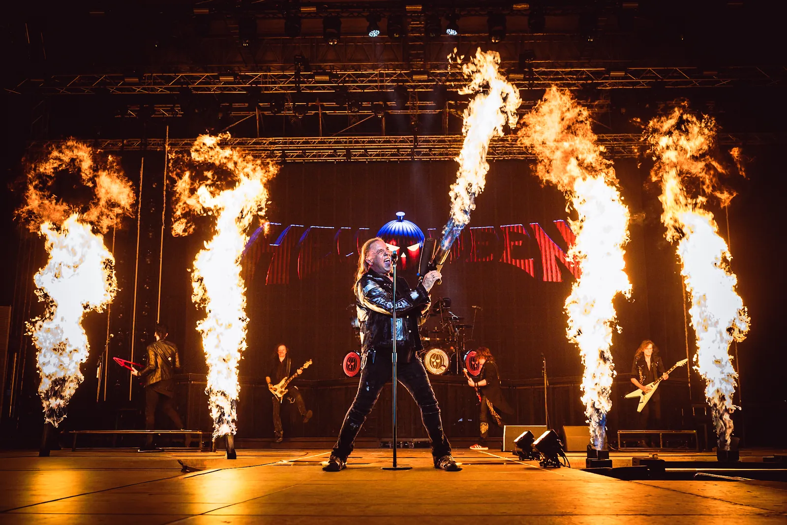 Sänger mit Flammenwerfer zwischen Pyro-Säulen auf der Bühne
